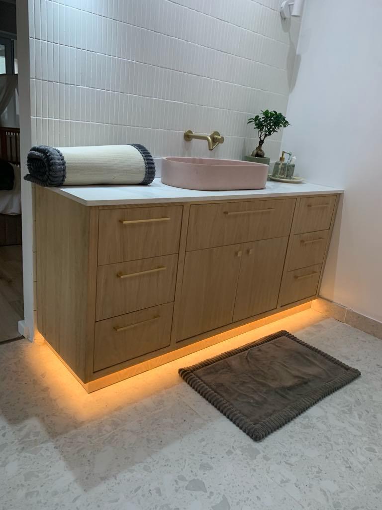Wide oak vanity with drawers either side of a blush-pink basin