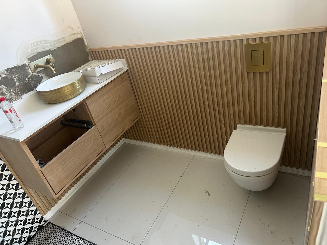 Guest bathroom with slatted oak wall panelling and a floating oak vanity